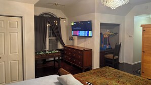 A bedroom with a bed, a dresser, a television, and a window with curtains.