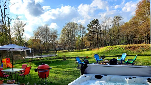 A backyard with a hot tub, patio furniture, and a trampoline.