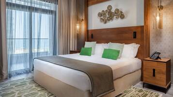 A hotel room with a large bed, a wooden headboard, a bedside table with a phone, and a decorative wall piece.