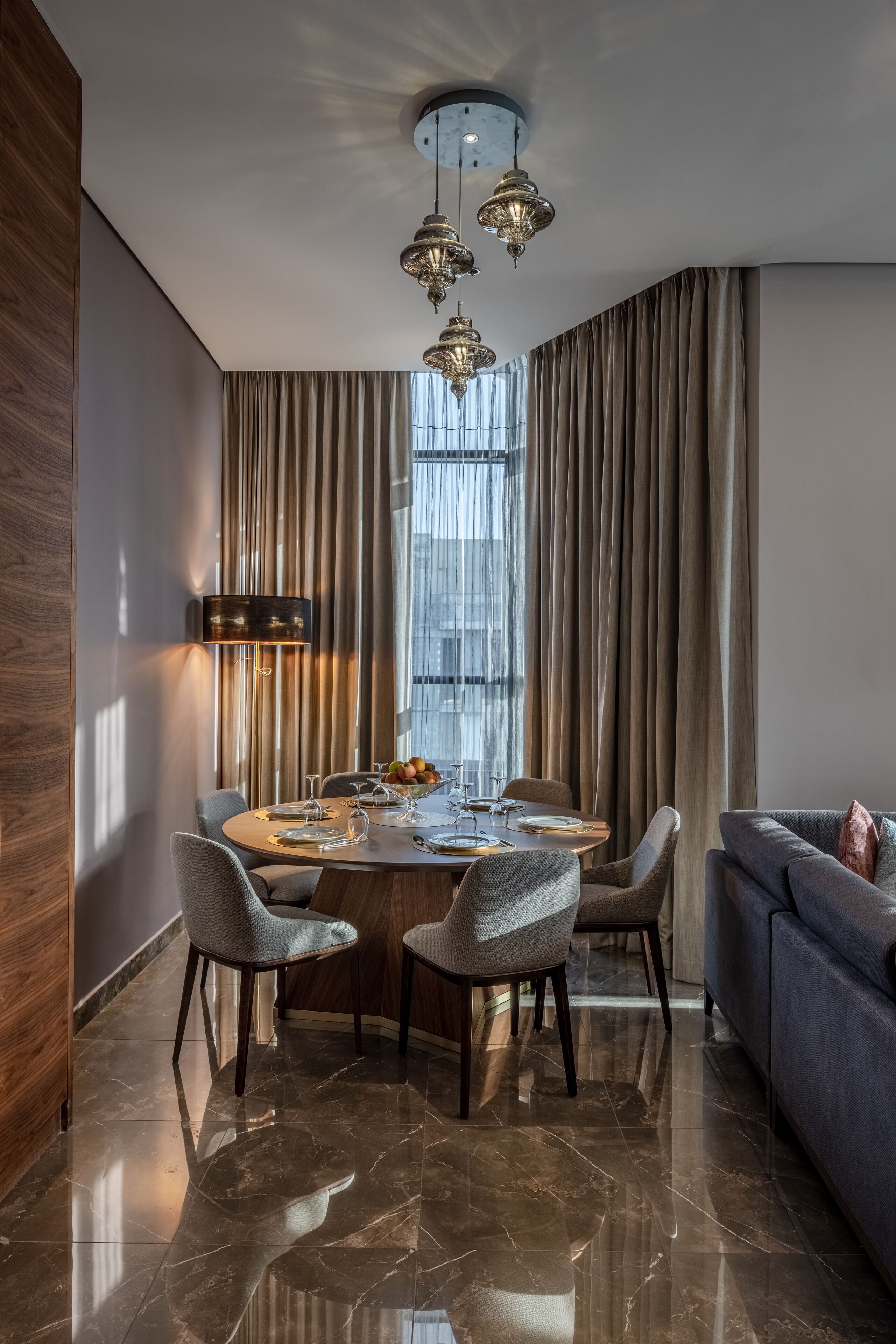A modern dining area with a round table, chairs, and a chandelier.