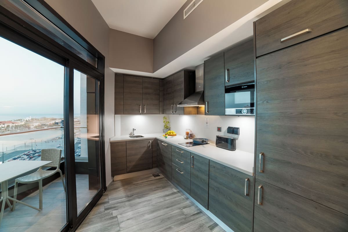 Una cocina moderna con armarios de madera oscura, una encimera blanca y vistas de la ciudad a través de amplias ventanas.