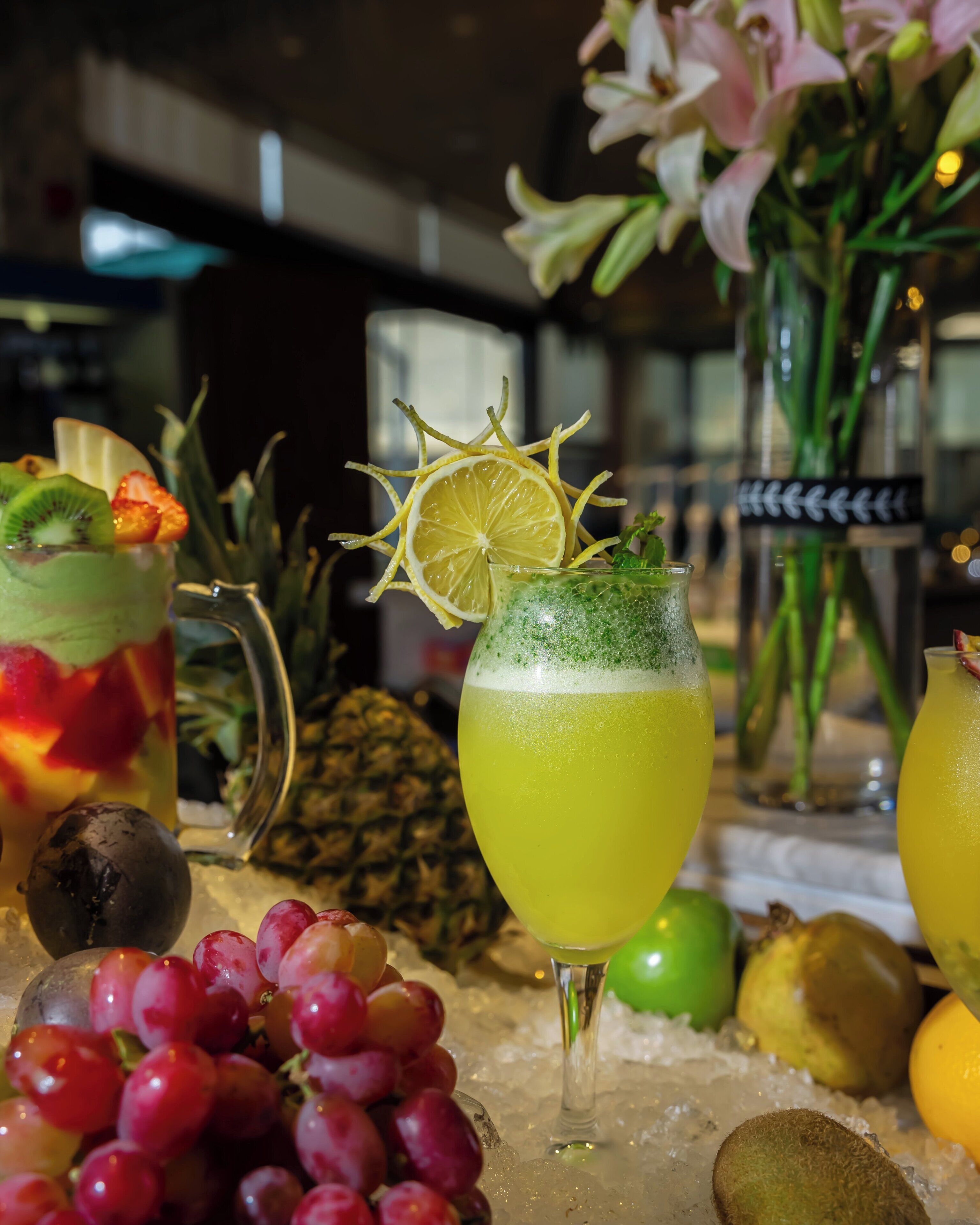 Zona de bar con frutas variadas y una bebida adornada con una rodaja de limón.