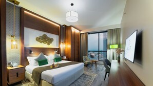 Quarto de hotel com uma cama grande, uma escrivaninha com cadeira, televisão e vista para a cidade.
