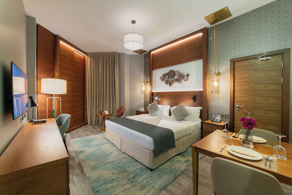 Una habitación de hotel moderna con una cama grande, mesitas de noche, un escritorio y un rincón de comedor.