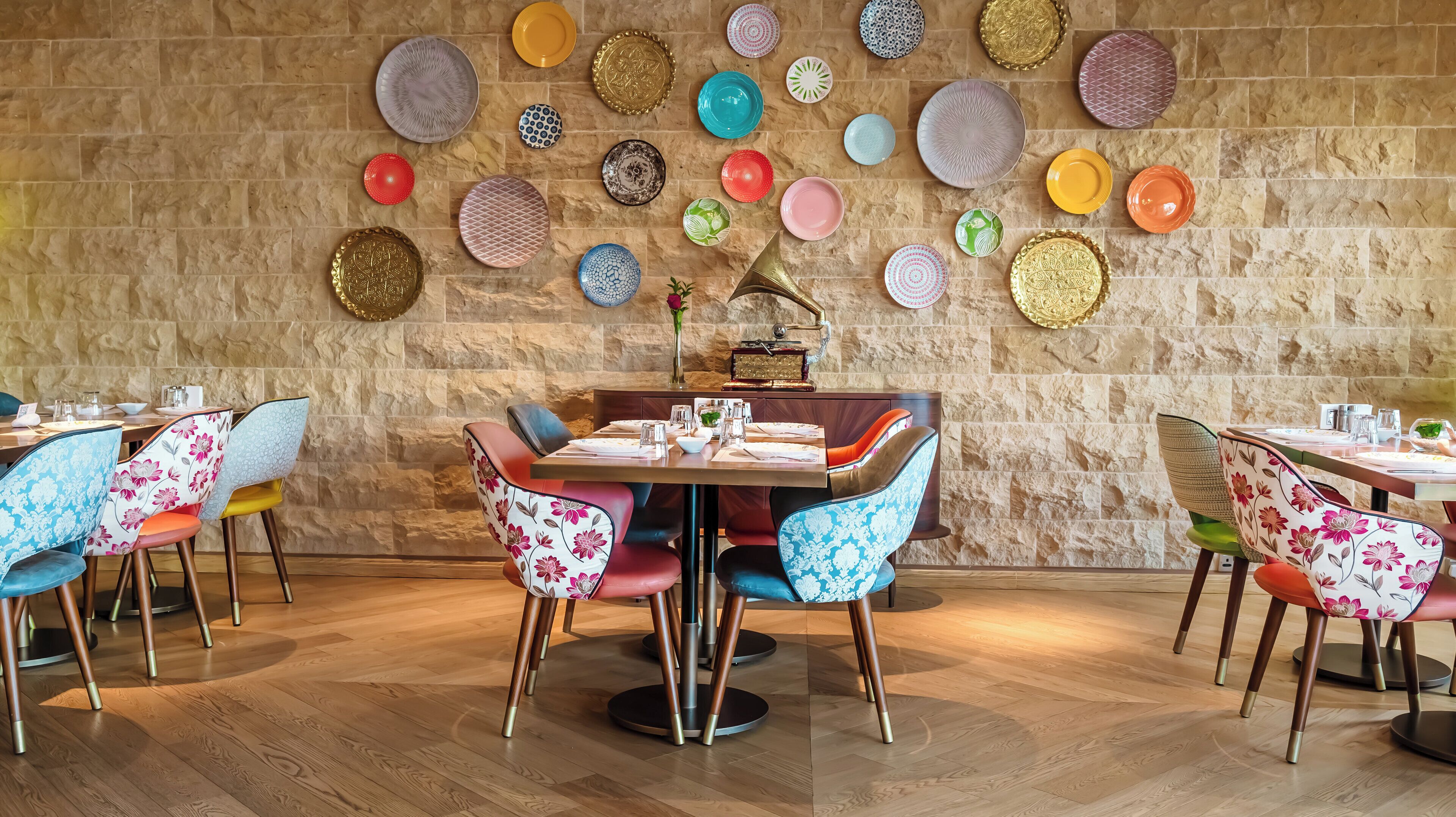 A restaurant with a stone wall and colorful plates hanging on it.