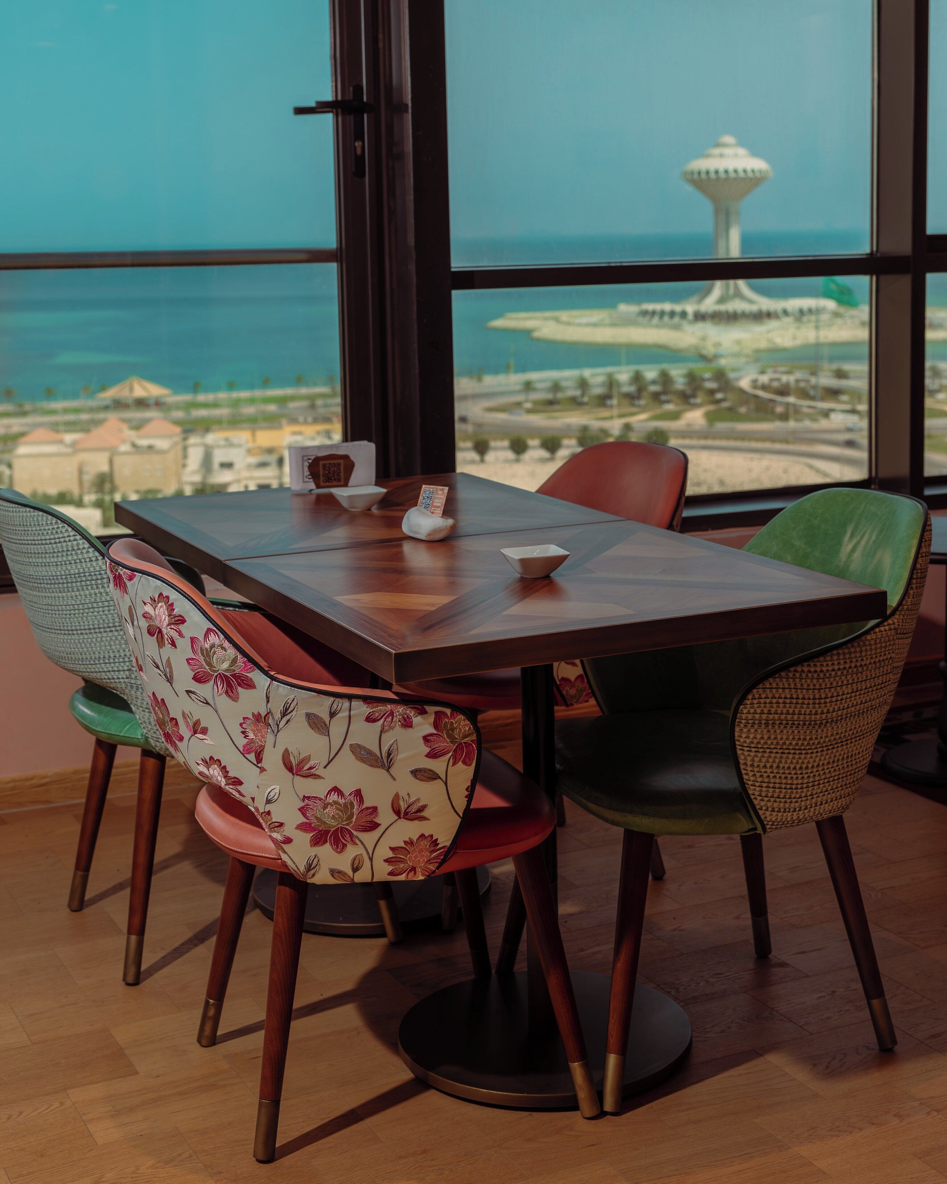 A dining area with a table and chairs, a view of a tower and landscape through large windows.