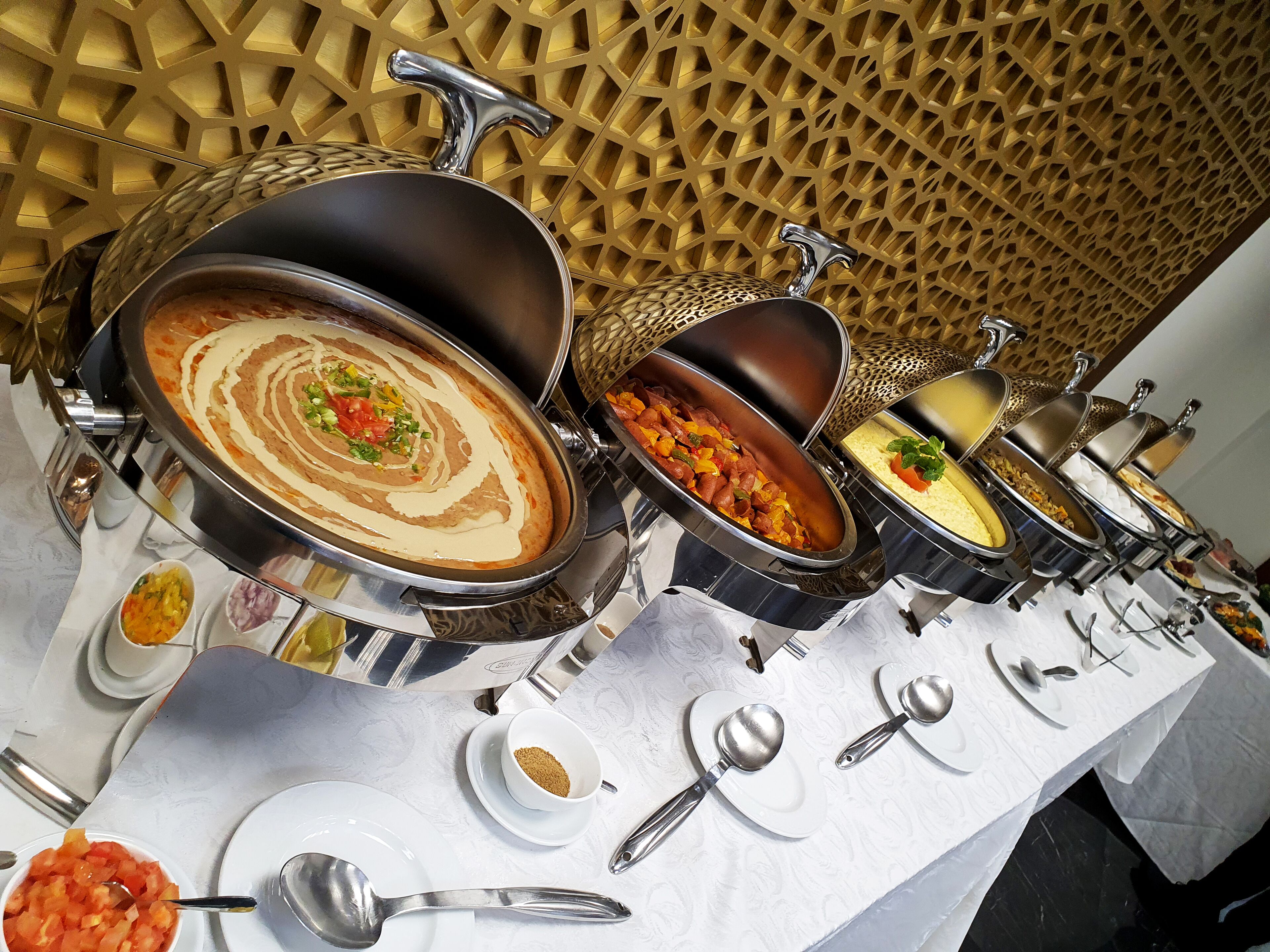 A buffet table with various dishes and utensils.