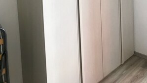 Une grande armoire à portes coulissantes et à poignée, située dans une pièce dont le sol est recouvert de parquet.