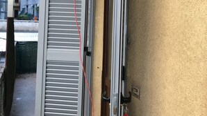 Une porte coulissante entrouverte, dotée d’un cordon rouge, d’une poignée en métal et d’un porte-clés avec une étiquette rouge.
