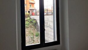 Une pièce dotée d’une grande fenêtre, d’un radiateur et donnant sur un immeuble d’habitation.