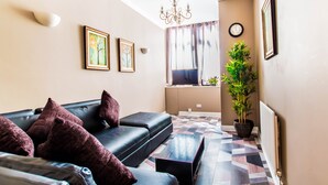 Una sala de estar moderna con un conjunto de sofá, una mesa de centro, una planta en maceta y un amplio ventanal con cortinas.