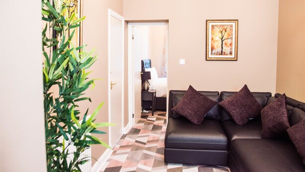Una sala de estar con un sofá, una planta en maceta y un cuadro en la pared.