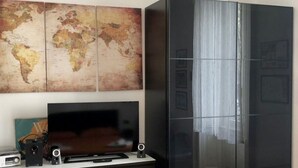 Une chambre moderne avec une grande carte du monde, un téléviseur à écran plat, une commode en bois foncé et une grande armoire noire.