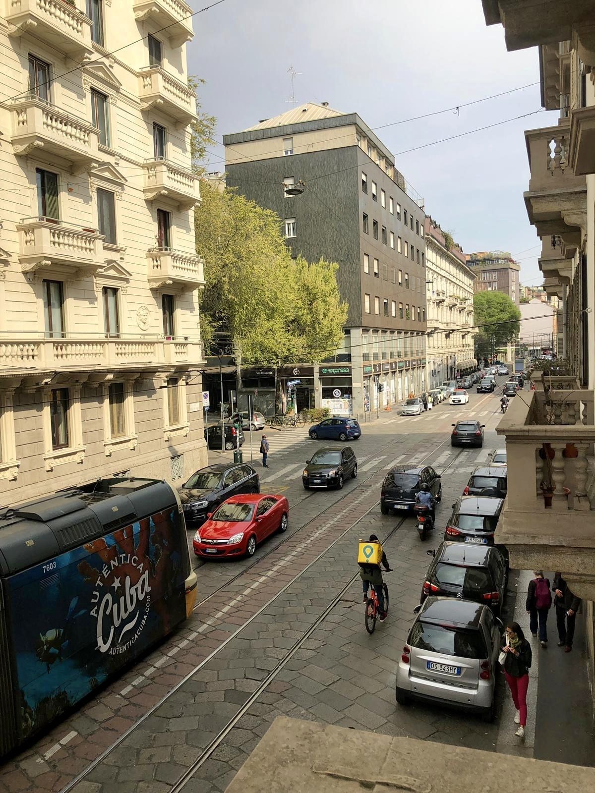 Straatbeeld met tramrails, geparkeerde auto's en gebouwen in klassieke stijl.
