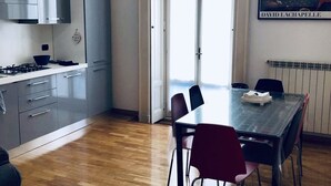 Une cuisine moderne avec des meubles gris, une cuisinière et un coin repas comprenant une table et des chaises.