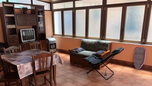 A room with a dining table, chairs, a sofa, a TV, and a window with frosted glass panes. - Calatafimi House Casa Vacanze Palermo (Palermo)
