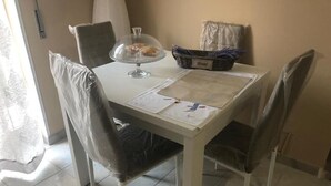 A dining table with a clear glass cake stand, a basket labeled "Bread," and papers on the table. - Calatafimi House Casa Vacanze Palermo (Palermo)