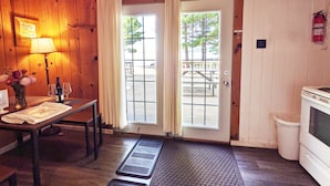 Une cabane en bois comprenant un coin repas, une cuisine et une porte donnant sur l’extérieur.