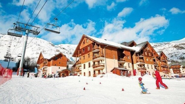 Un centro de esquí con edificios de madera, remontes y laderas cubiertas de nieve.