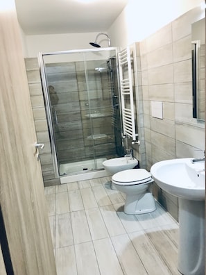Un baño moderno con ducha envuelta en vidrio, inodoro y lavamanos.