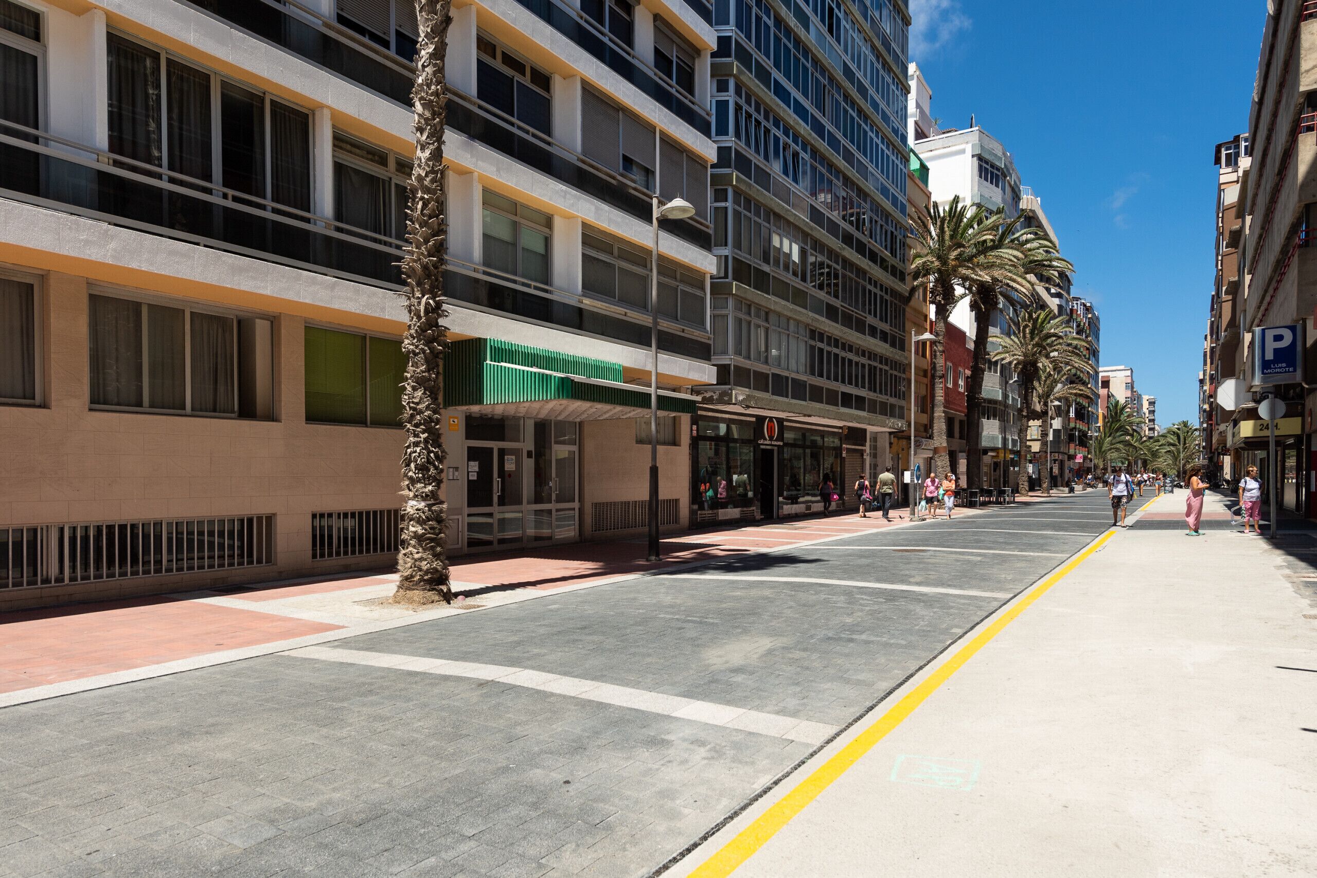 A multi-story building with a ground-level commercial space and a parking area.