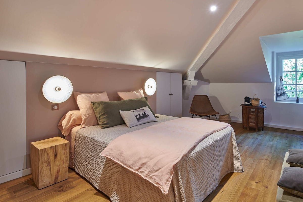 A bedroom with a bed, bedside tables, a chair, and a window.