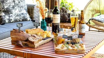 Una mesa de madera con pan, queso y botellas de vino.