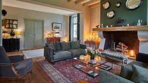 A cozy living room with a sofa, armchairs, a coffee table, and a fireplace. - Bel Air Maison D'hôtes des Landes (Castets)