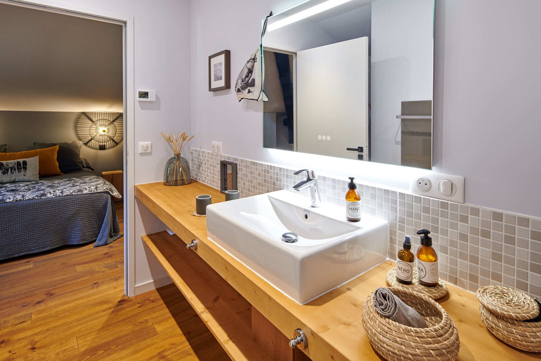 Une salle de bain moderne avec un grand lavabo, un miroir et un meuble-lavabo en bois.