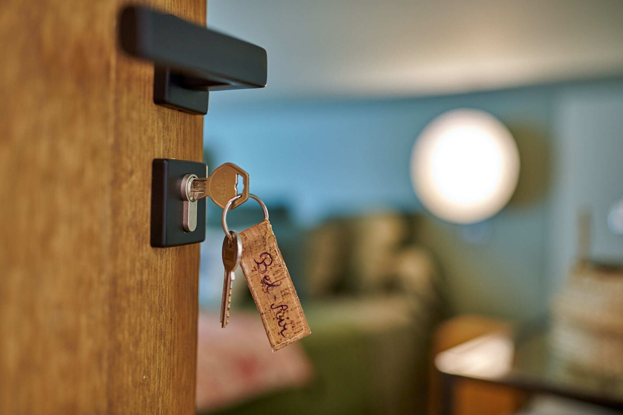 A wooden door with a keyhole and a cork tag hanging on a keyring.