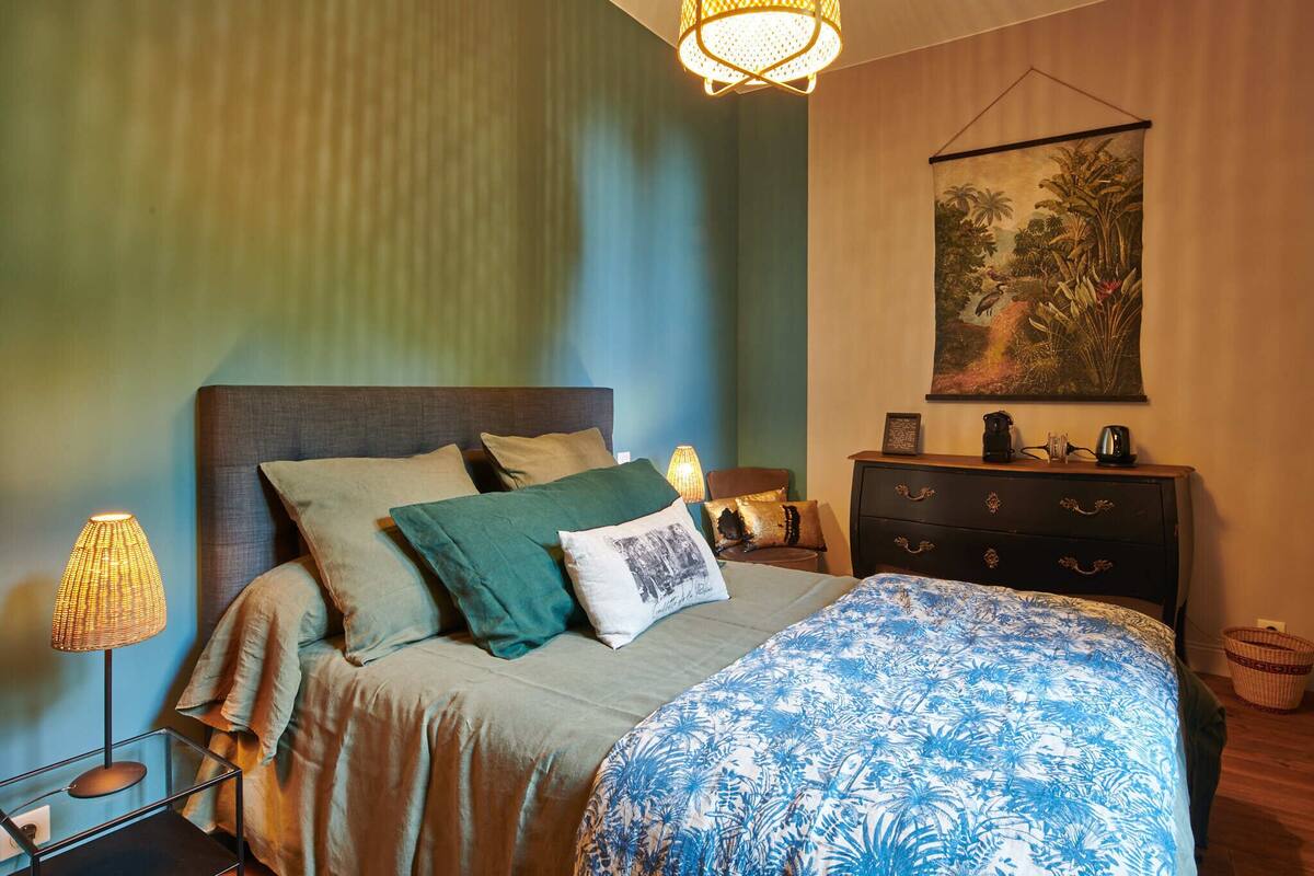 A bedroom with a bed, nightstands, a dresser, and a wall tapestry.