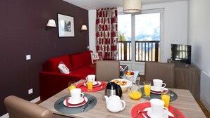 A dining area with a table set for breakfast, including plates, cups, and a coffee pot.