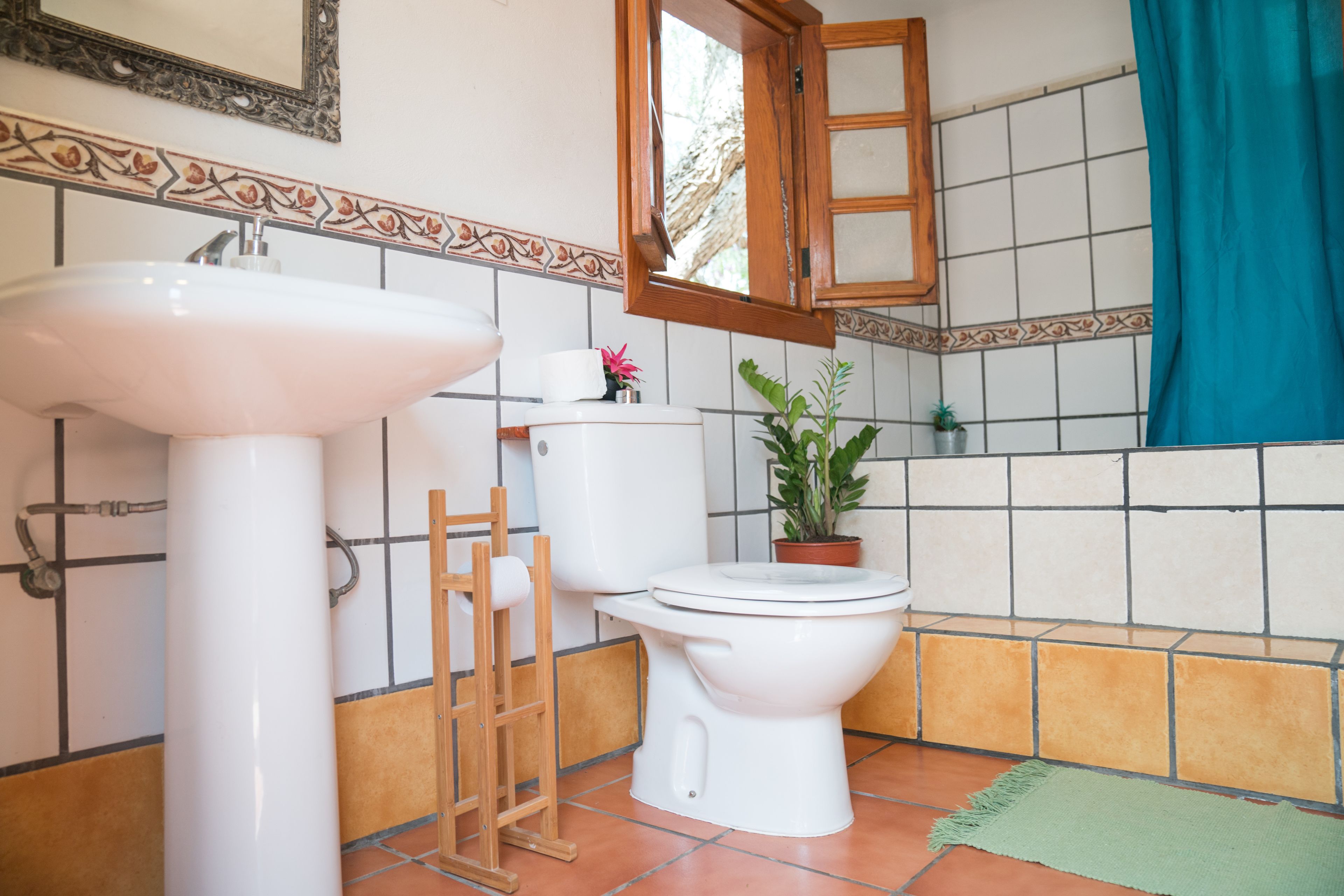 A bathroom with a white sink, toilet, and a wooden ladder.