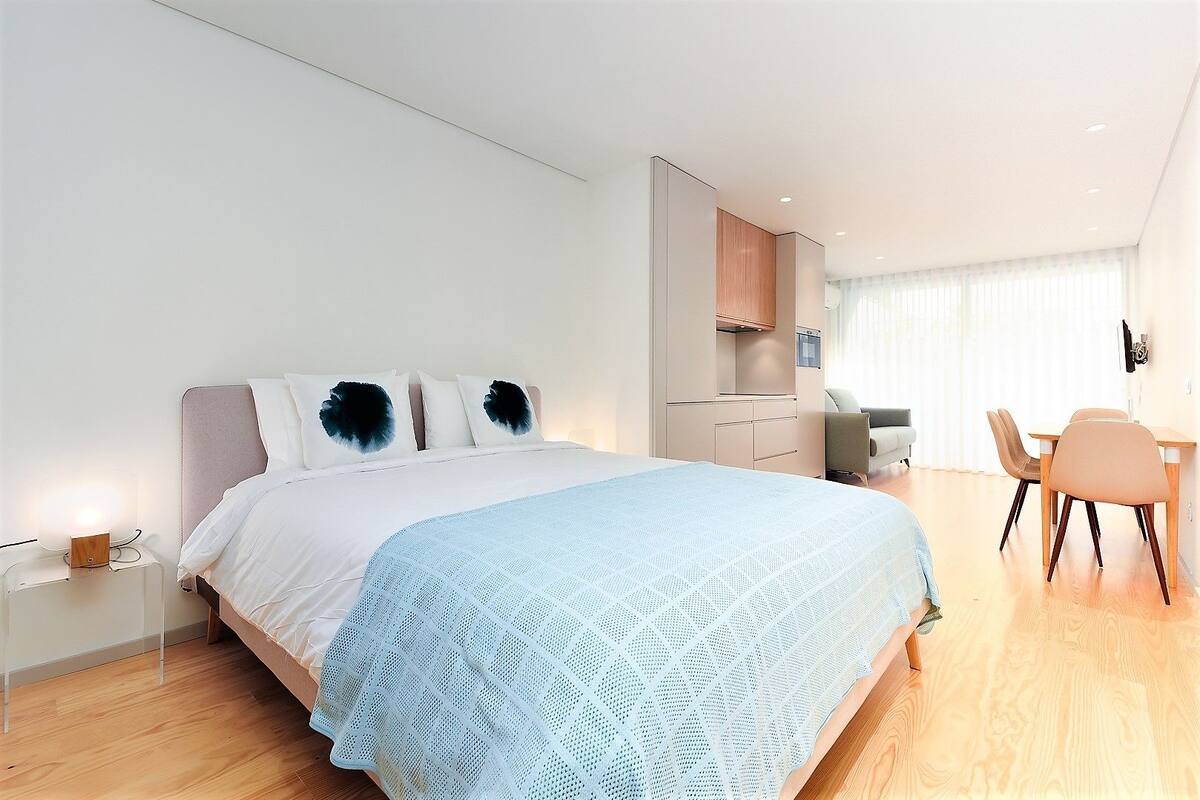 A modern hotel room with a large bed, a desk, and a chair.