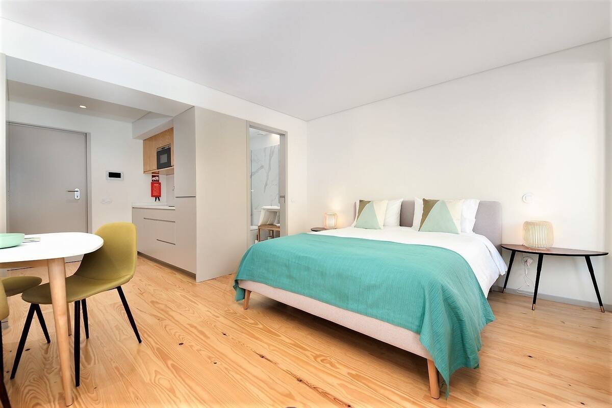 A modern bedroom with a bed, bedside tables, a desk, and a chair.