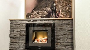 Una chimenea con revestimiento de piedra, un cuadro enmarcado encima y piso de baldosas.