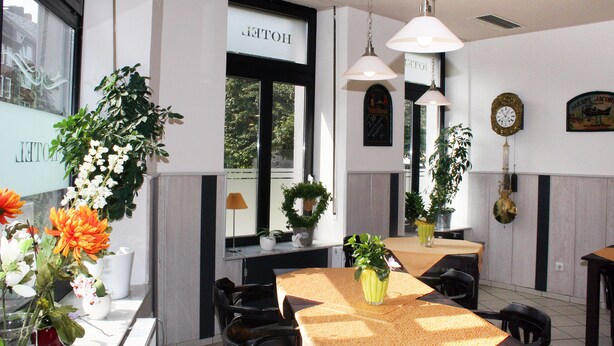 A hotel dining area with tables, chairs, and potted plants. - Hotel Klenkes am Bahnhof (Aachen)