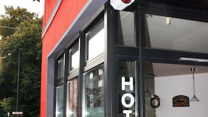 A hotel with a red facade, large windows, and flower boxes on the ground floor. - Hotel Klenkes am Bahnhof (Aachen)