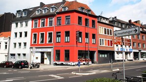 A red and white building with a sign for 'Music Dreams' and a directional sign for 'Hauptbahnhof'. - Hotel Klenkes am Bahnhof (Aachen)