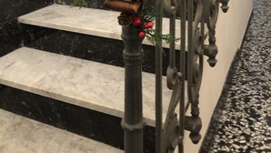 A staircase with black marble steps, a wooden handrail, and a metal railing with intricate designs. - Meliora Rooms (Avola)
