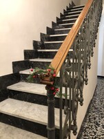 Una escalera con escalones de mármol negro, barandilla de madera y una baraja metálica con detalles intrincados.