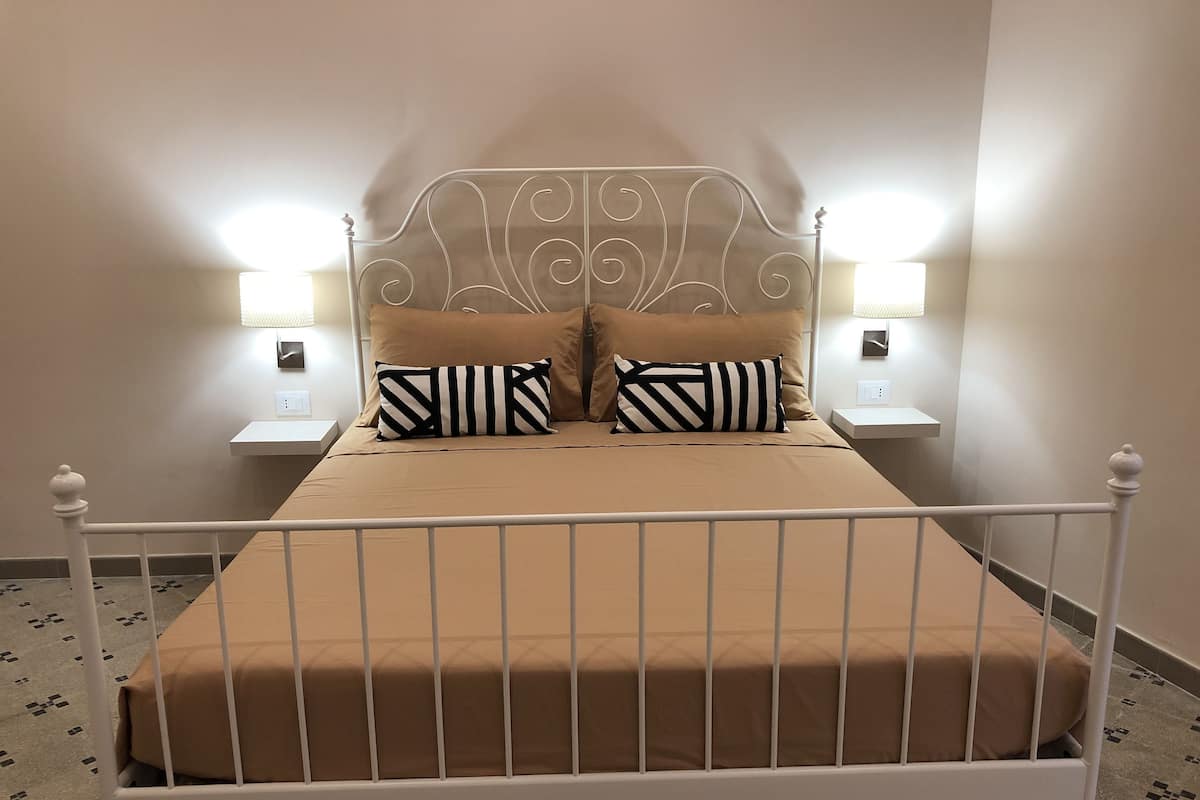A bed with a metal frame, two pillows, and two bedside lamps.