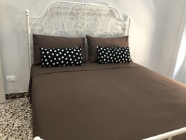 Una cama con cabecera de metal blanco, dos almohadas marrones y una colcha marrón.