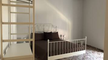 Ein Schlafzimmer mit Bett, Nachttisch, Lampe, Kleiderschrank und Klimaanlage.