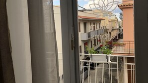 A balcony with a view of neighboring buildings and a decorative metal gate. - Meliora Rooms (Avola)