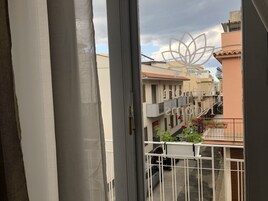Un balcón con vista a edificios vecinos y una reja decorativa de metal.