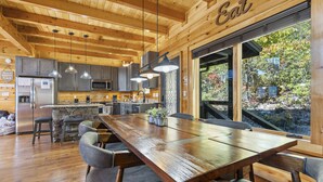 Una cocina amplia con vigas de madera, una gran mesa de comedor y vistas al exterior.