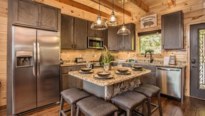 Una cocina moderna con encimeras de granito, electrodomésticos de acero inoxidable y vigas de madera.