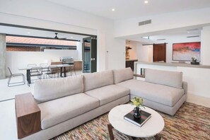 A modern living room with a large L-shaped sofa, a round coffee table, and a dining area with a kitchen visible through an open door. - Marine Life—Coastal Retreat Near Busselton Jetty (Busselton)