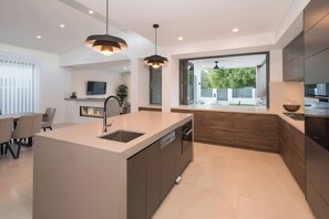 A modern kitchen with a central island, built-in appliances, and pendant lighting. - Marine Life—Coastal Retreat Near Busselton Jetty (Busselton)